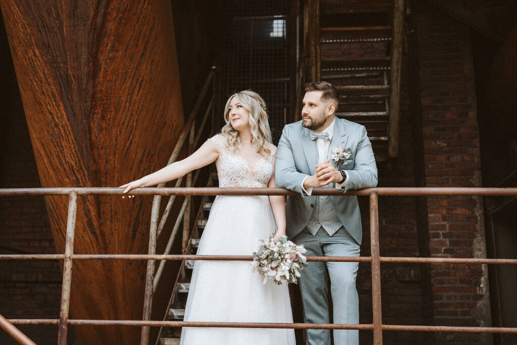 Braut und Bräutigam stehen vor einem Hochofen im Landschaftspark Duisburg
