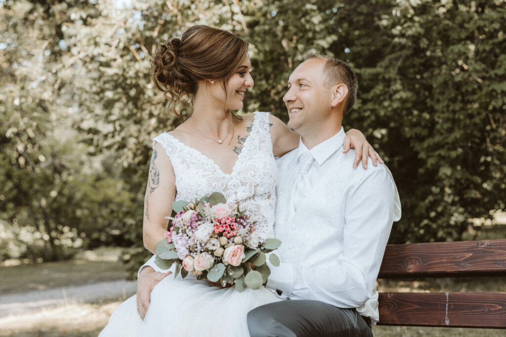 Braut und Bräutigam stizen auf einer Bank im Stadtpark Moers