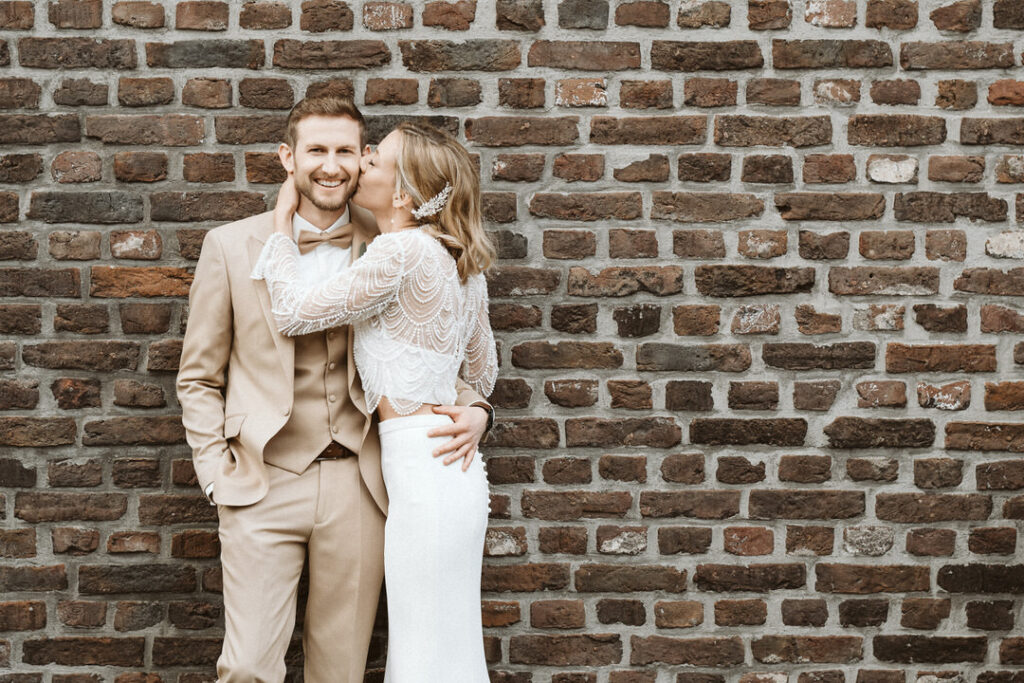 Braut küsst Bräutigam auf die Wange auf dem Feltgenhof in Moers