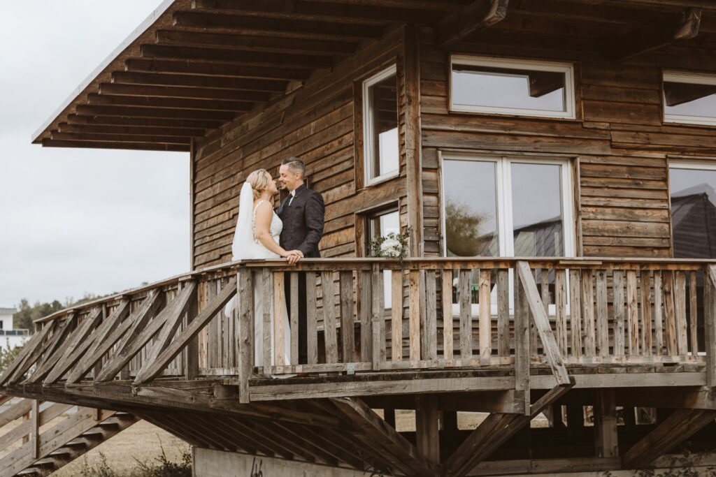 Brautpaar steht an einem Holzhaus in Dinslaken