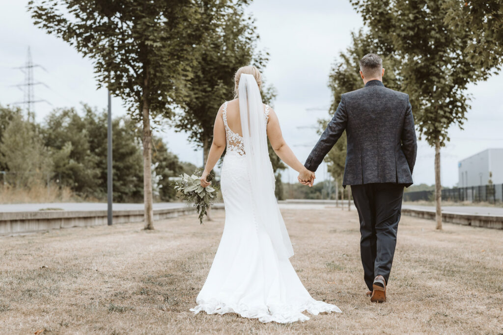 Brautpaar läuft von hinten richtung Hochzeitslocation Zeloh