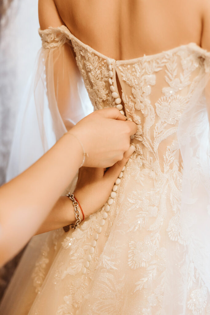 Detailaufnahme des zuknöpfen des Brautkleides