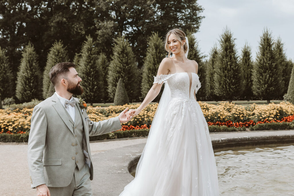 Braut und Bräutigam spazieren am Brunnen im Kloster Garten in Kamp Lintfort