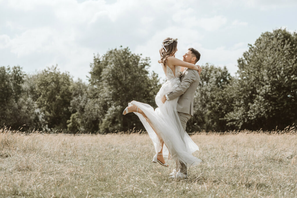 Bräutigam hebt seine Braut hoch im Feld