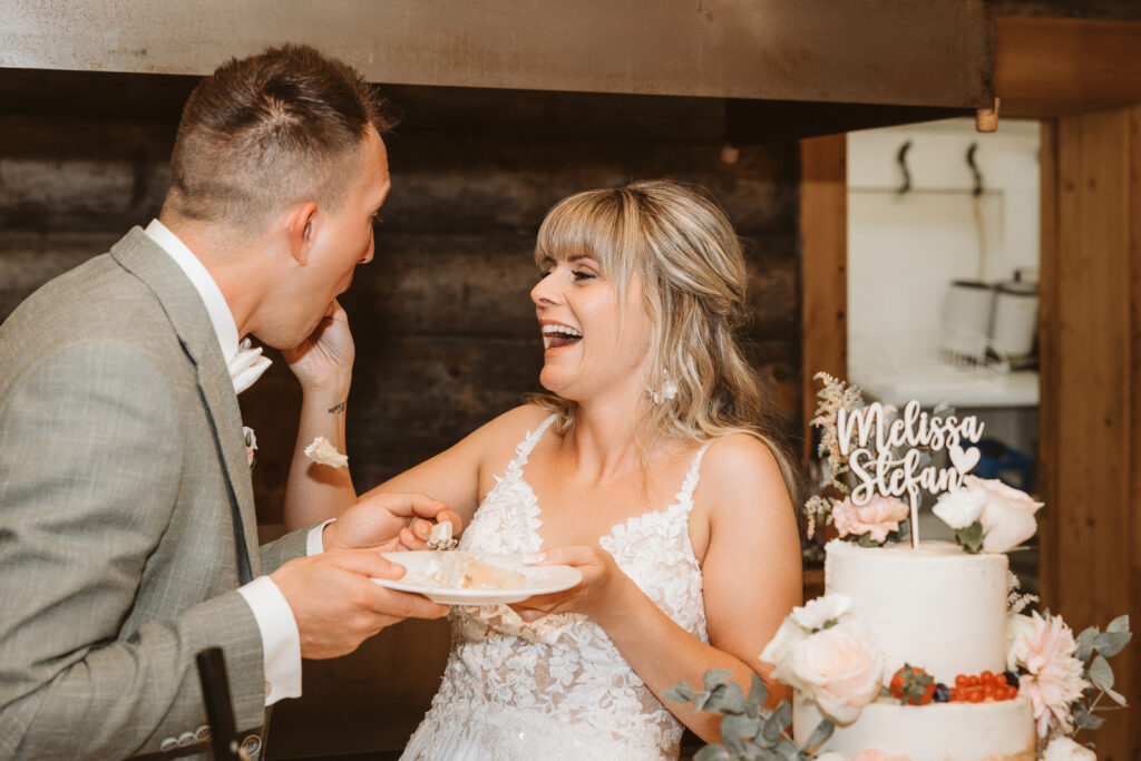 Braut füttert den Bräutigam mit der Hochzeitstorte